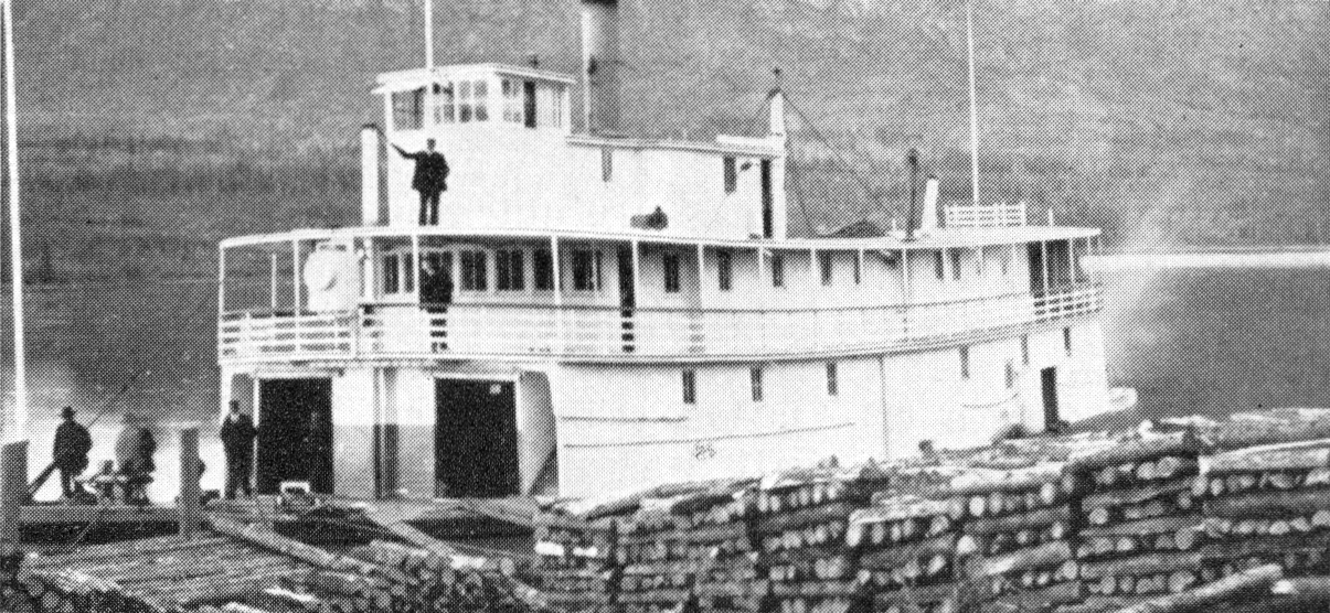 A steamboat docked next to massive piles of logs